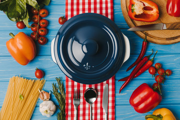 top view of pan and unprocessed vegetables and pasta on blue table