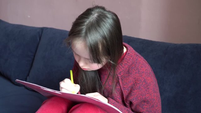 	Down syndrome girl is drawing at home