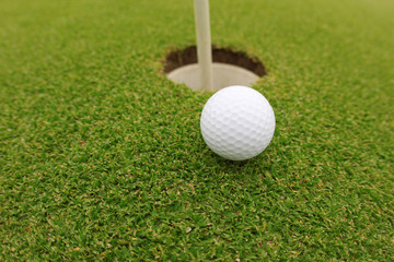 Golf ball on the green near the hole