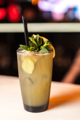 Ginger cocktail with lemon and mint on the white bar