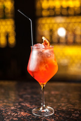 A glass of red cocktail with grapefruit on the bar