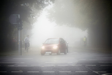 Stra&szlig;enverkehr im Nebel  / Stra&szlig;enverkehr mit Radfahrern und Autos morgens im Nebel.