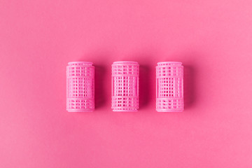 top view of pink curlers on pink background