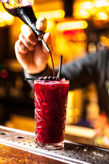 Close-up of expert bartender making red blueberry cocktail in bar