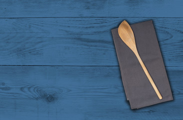 Kochlöffel und Küchentuch auf blauem Holzuntergrund