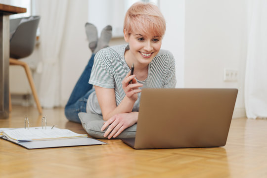 Young cheerful woman working with laptop on floor