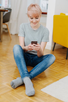 Pretty woman sitting on the floor texting