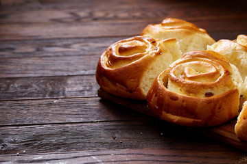 Homemade rose buns on wooden cutting board over rustic vintage background, close-up, shallow depth of field