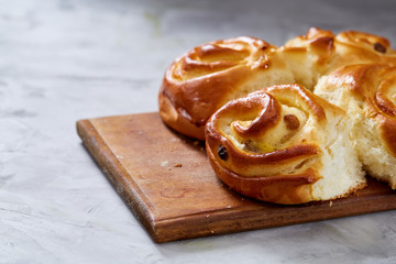 Homemade rose buns on wooden cutting board over white textured background, close-up, shallow depth of field