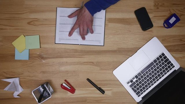 Man types on laptop and writes down notes. Freelancer working in office. Business man and computer