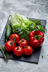 Close-up still life of assorted fresh vegetables and herbs on white textured background, top view, selective focus.