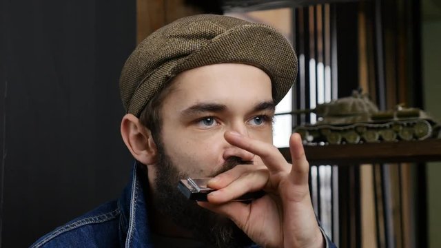 Musician plays the harmonica. Young men enjoying music by harmonica. Close-up portrait of expressive young man playing harmonica.