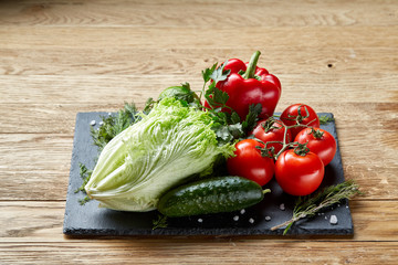 Close-up still life of assorted fresh vegetables and herbs on wooden rustic background, top view, selective focus.