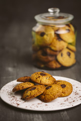 Chocolate cookies placed on a plate on a dark background.