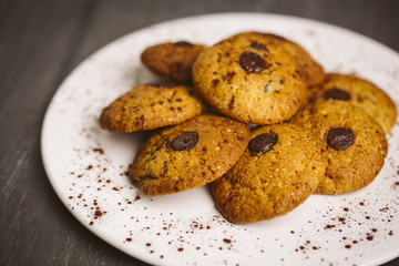 Chocolate cookies placed on a plate on a dark background.