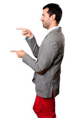 Handsome man pointing to the lateral on isolated background
