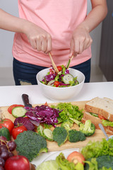 close up woman mixing salad while cooking in kitchen