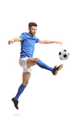 Soccer player jumping and kicking a football