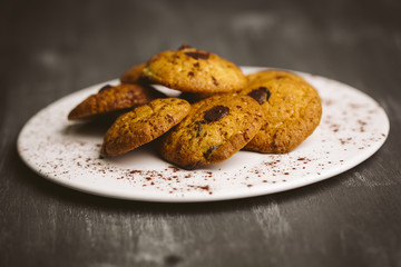 Chocolate cookies placed on a plate on a dark background.