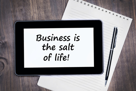 Business is the salt of life! Text on tablet device on a wooden table