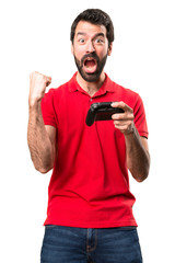 Lucky handsome young man playing videogames over isolated white background