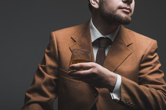 Handsome bearded businessman is drinking expensive whisky closeup. tonned image