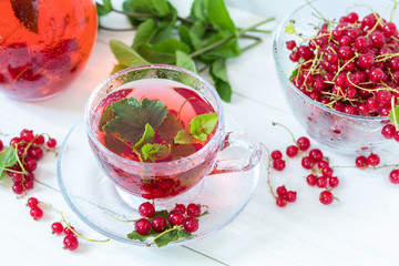 Redcurrant drink in transparent glass carafe and cup