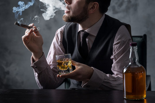 Man drinks whiskey and smokes cigare