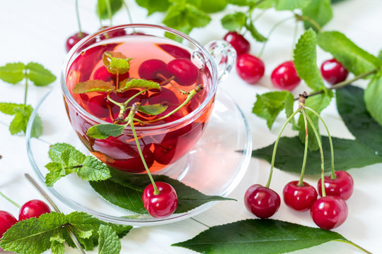 esh fruit cherry drink in transparent glass cup surrounded by cherries