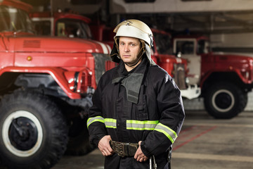 Fireman (firefighter) in action standing  near a firetruck. Emergency safety. Protection, rescue from danger.