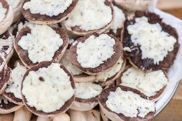 Preparing mushrooms for barbecue on holiday. Mushrooms with cheese spread in bowl. Cooking vegetables. Delicious meal for vegetarians and vegans.