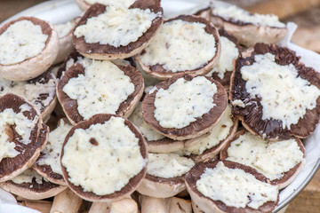 Preparing mushrooms for barbecue on holiday. Mushrooms with cheese spread in bowl. Cooking vegetables. Delicious meal for vegetarians and vegans.