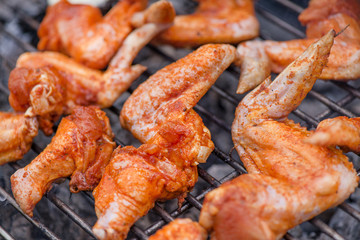 Chicken wings on barbecue grill on hot charcoal and fire. Spicy marinated chicken meat  cooking over the flames