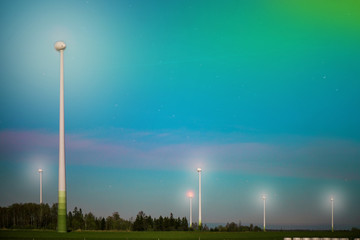 Abstract shot of wind turbines in the meadow on starry night sky background. Falling stars. Rural...