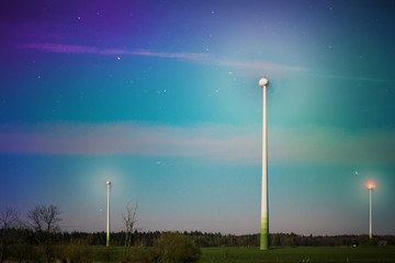 Abstract shot of wind turbines in the meadow on starry night sky background. Falling stars. Rural...