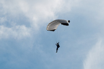 Parachutist with White Parachute against Clear Blue Sky
