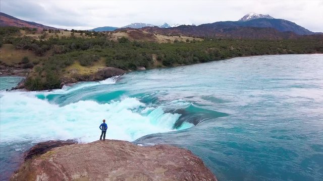 Hiker stands on the coast of powerful river. Aerial view of the rapids of river of Baker. Patagonia, Chile