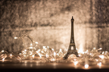 The Eiffel model is placed on a wooden table surrounded by light. Blurry background.