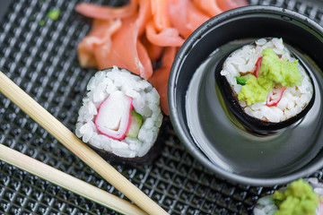 Fresh and delicious maki and nigiri sushi rolls with tiger shrimps, salmon, philadelphia cheese and wasabi served with soy sauce and ginger slices on black take away plate. Japanese food in restaurant