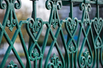 Abstract macro shot of green metal bridge railing in city centre. Beautiful heart shaped ornament decorations. Concept of love