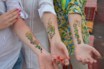 three girls show henna tattoos on their hands
