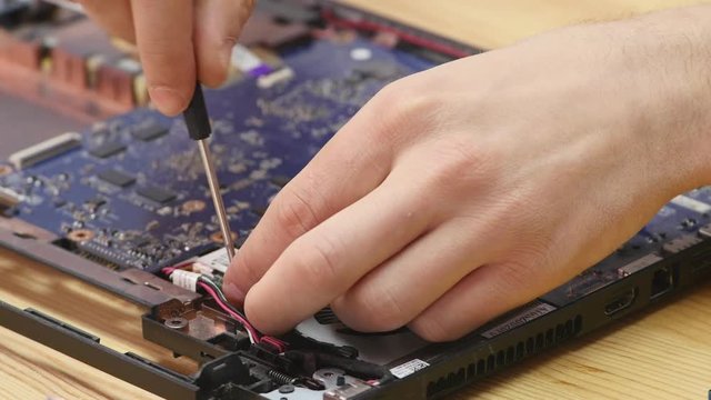 Laptop disassembling in repair shop, close-up. Disassembled computer motherboard on repairman workplace. Electronic development, technology fixing concept