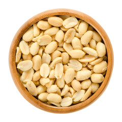 Peanuts, roasted and salted, in wooden bowl. Shelled Arachis hypogaea, also called groundnut and goober, used as a snack. Isolated macro food photo close up from above on white background.