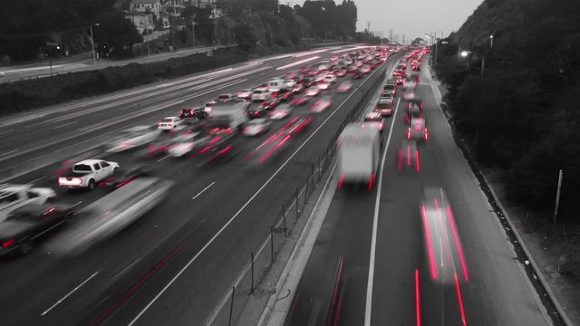 Time Lapse of traffic where the footage has been made black and white except for the red of the car's taillights.