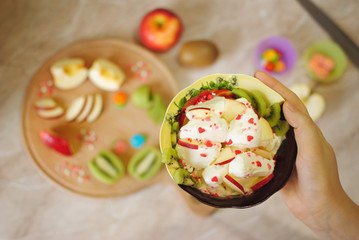 Завтрак из фруктов. Фруктовый десерт с мороженым. Киви и яблоко на кухонной круговой деревянной доске. Кусочки фруктов. Здоровая пища. Полезные сладости.
