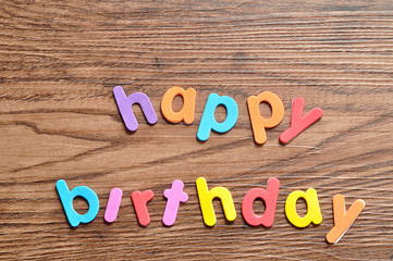 Happy birthday in colorful letters on a wooden background