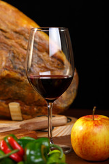 a glass of red wine on a background of Spanish ham jamon in a low key. Drink aperitiv and tapas