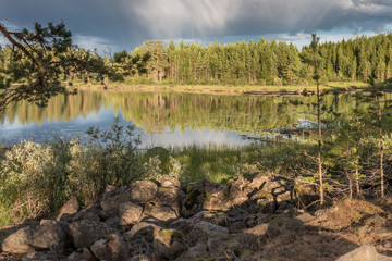 Beautiful Scandinavian lake with reflections of forest and sky in evening light  