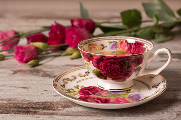 cup of tea  and a red flowers on wooden background