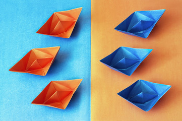 Origami. Blue and orange paper boats on a contrasting background